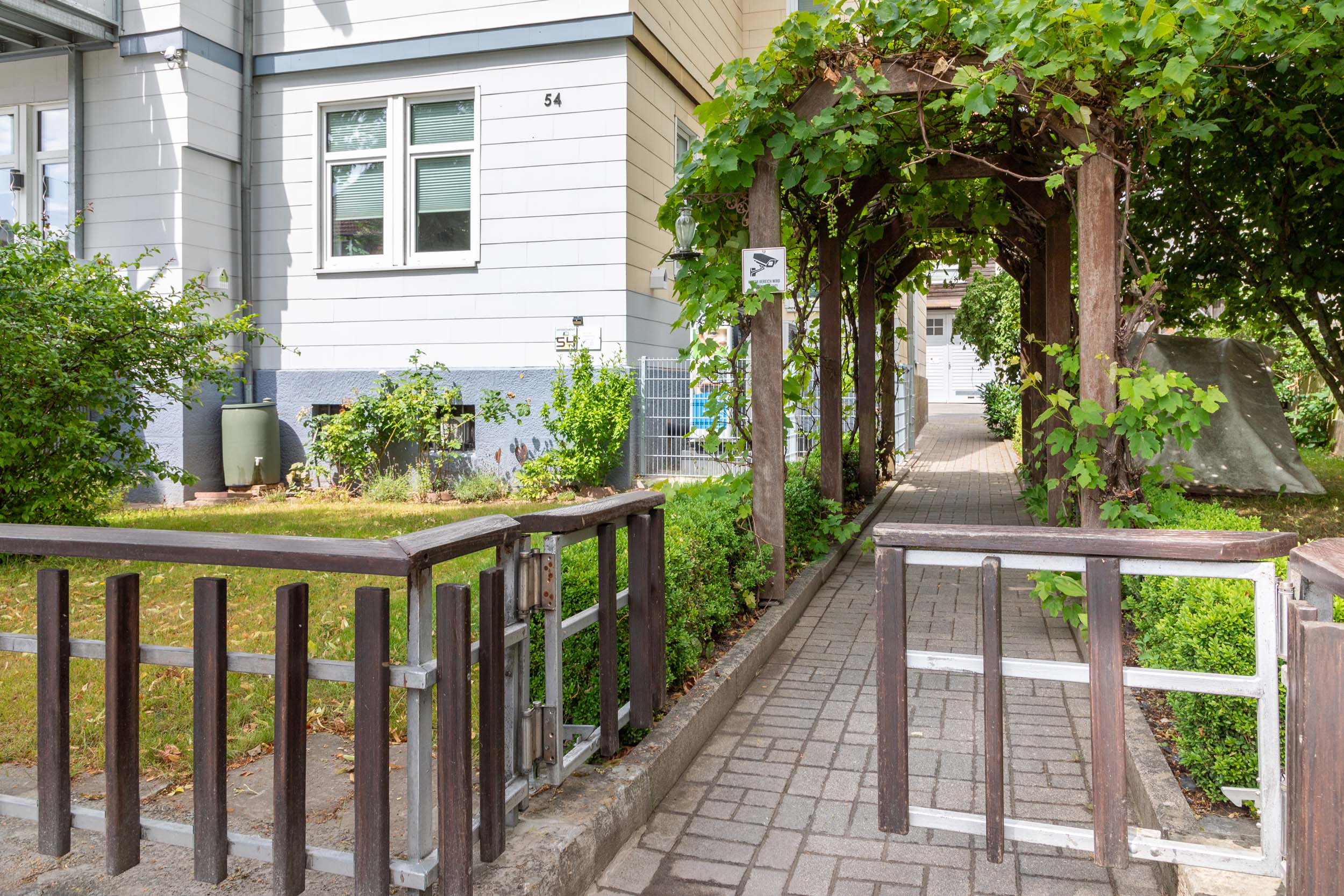 Schöner Gartenbereich mit einer überdachten Passage zum Eingang